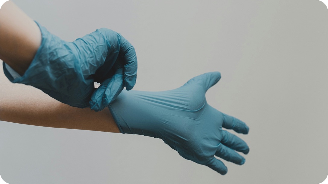 A clinician pulling on a pair of surgical gloves